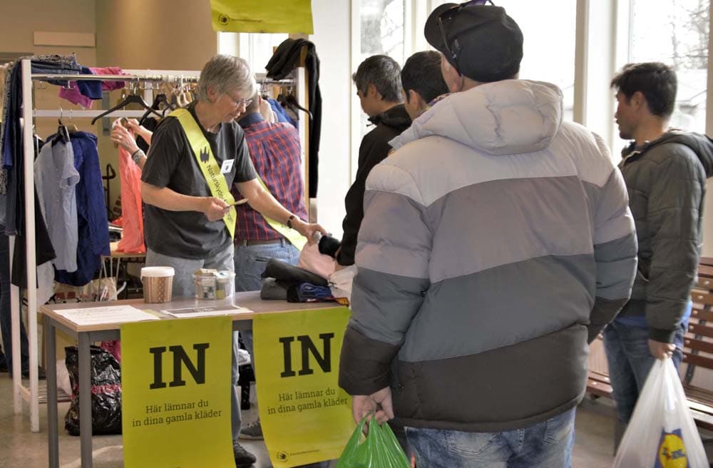 Tre män står i kö för att lämna in kläder på klädbytardagen 2019