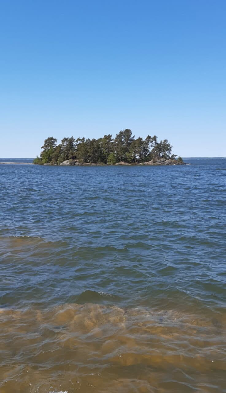 Vänersnäs skärgård man ser ett vattenbryn och i blickfånget längre ut en beskogad ö.