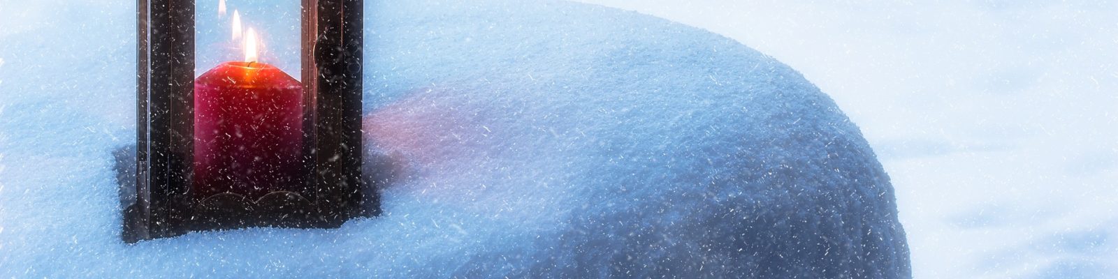 Rött blockljus i snölykta placerad på snötäckt sten.